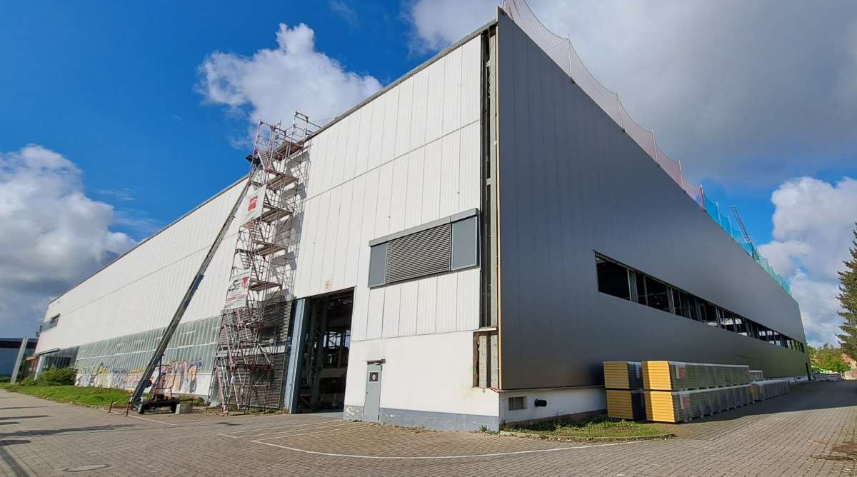 Ansicht Gebäude Ecke Nordost (Blick Gebäude von Hauptzufahrt), Bestandsfassade an Ostseite mit neuer Isopaneelfassade an Nordseite. Foto: hpm Henkel Projektmanagement GmbH