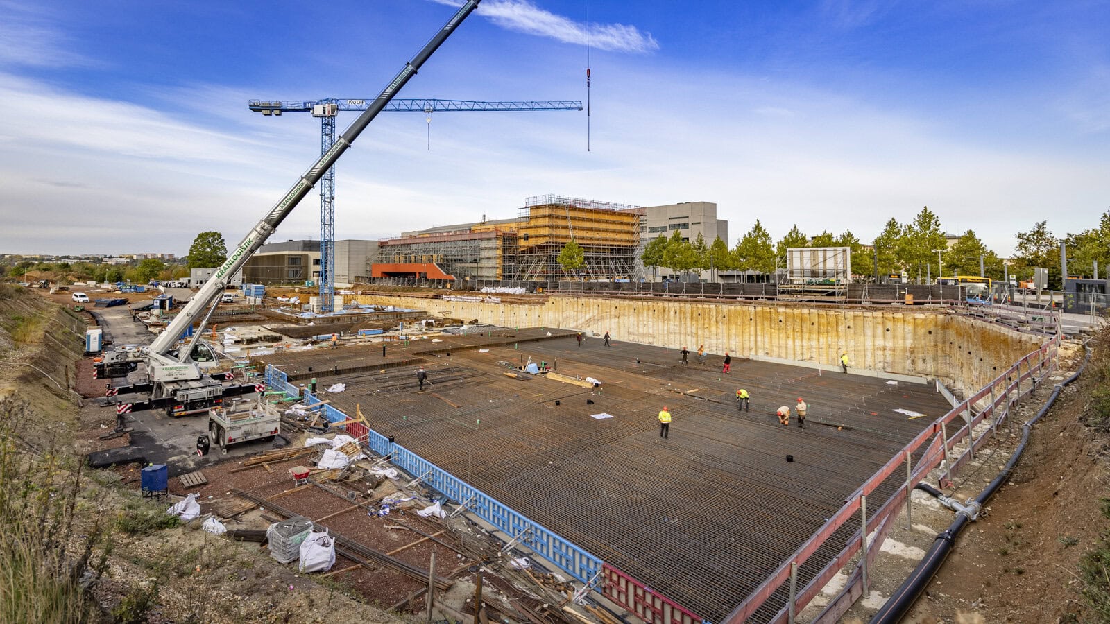 Großbaustelle auf dem Campus: In der Baugrube des Chemie-Gebäudes entsteht aktuell stufenweise die Bodenplatte. Das Richtfest für dieses Gebäude soll im Dezember 2027 stattfinden. Im Hintergrund ist das eingerüstete Zentrale Hörsaal- und Seminargebäude zu sehen. Die Arbeiten an der Fassaden und am Dach sind voraussichtlich zum Jahreswechsel beendet. Foto: Jacob Müller